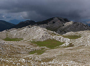 Il caratteristico paesaggio carsico del piano apicale del Monte Cervati, sullo sfondo s’intravede la chiesetta della Madonna della Neve.