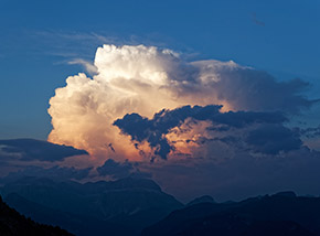 Un grande cumulo sopra la Val di Fassa si illumina con gli ultimi bagliori di luce.