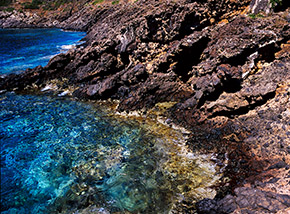 Acque turchesi e cristalline lambiscono le nere rocce vulcaniche di Ustica (Cala S.Paolo).