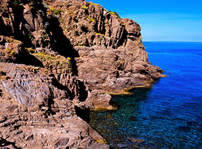 Scorcio sulle rosse scogliere che delimitano Cala dello Zurletto.