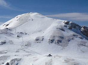 Vista sul Rifugio Vincenzo Sebastiani al Colletto di Pezza, dietro cui si alza il Costone (Vetta Orientale).