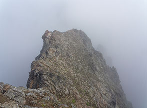 Profili di roccia si perdono tra la nebbia sulla Cresta Nord della Becca di Nona.