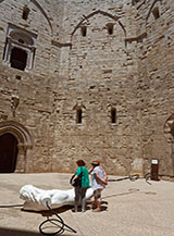 Turisti nel cortile di Castel del Monte (scultura di Nino Longobardi).