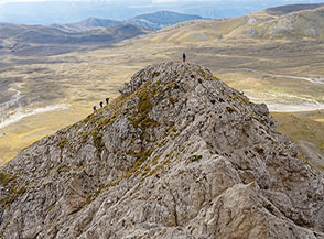 Appenninisti sulla Cima Bifida Meridionale di Monte Faeto, sullo sfondo al sole i prati di Campo Imperatore.