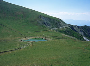 Il Lago di Camarda incastonato sulla sella prativa del Piano di Camarda.