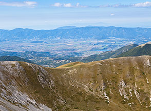 La prativa Sella di Vall&rsquo;Organo (al centro), sullo sfondo la Piana Reatina con i laghi di Ripa Sottile e Lungo.