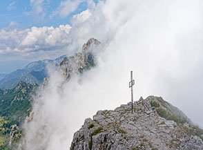 La croce di Cima Baffelan, sullo sfondo per un attimo le nuvole lasciano intravedere anche la cima del Monte Cornetto.