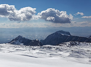 Vista a valle: in primo piano le sagone scure del Monte Etra (sulla sx) e del Monte Tino o Serra di Celano (sulla dx), sullo sfondo la Piana del Fucino.