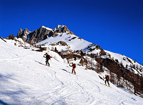 Scialpinisti risalgono il pendio ai piedi della Colonia Alpina di Valle Stretta.