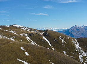 Il Monte Calvo (si scorge appena la croce sommitale) visto da Colle di Mezzo con la bianca Majella che si allunga all&rsquo;orizzonte.