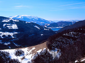 Uno spicchio del Lago di Campotosto fa capolino fra i fianchi boscosi della Valle del Rio Fucino.