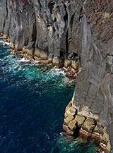 Un muro di nero basalto fronteggia la pressione del mare a Ponta das Eiras.