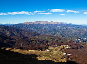 Prati di Tivo accerchiata dai boschi e dalla sinistra ombra del Corno Piccolo, all&rsquo;orizzonte la catena della Laga.