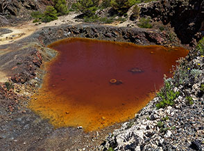 Il laghetto di acque rosse nell&rsquo;area di carico delle Miniere di Calamita a Punta di Vallemorta.