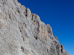 Vista verso il Bivacco Bafile, sperduto puntino rosso nel severo paesaggio di croda del versante sud-orientale del Corno Grande.