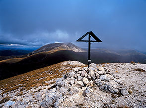 Il piccolo crocefisso sulla cima di Monte i Porcini, sullo sfondo il Monte di Cambio.