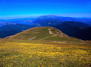 Sul dolce pendio a nord dello Ienca in vista del Morrone (primo piano), il Lago di Campotosto e la Laga.