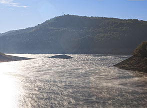 Sbuffi di vapore danzano all&rsquo;unisono sulle placide acque del Lago di Pietra del Pertusillo.