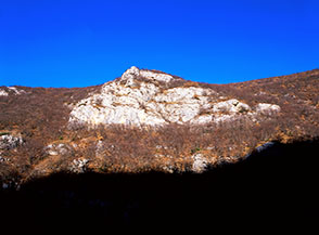 La luce del mattino illumina un grande balzo di roccia in Valle Donica mentre il fondovalle &egrave; ancora immerso nel buio.