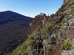 Scorcio sul sentiero che dal Pas de Bellecombe cala a svolte sul fondo dell&rsquo;immenso plateau vulcanico del Piton de la Fournaise.