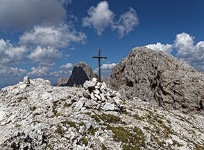 L&rsquo;umile croce sulla Cima Sud-Ovest delle Coronelle, alle sue spalle la di poco pi&ugrave; alta Cima delle Coronelle (l&rsquo;apparenza inganna!).