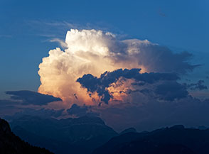 Un grande cumulo sopra la Val di Fassa si illumina con gli ultimi bagliori di luce.